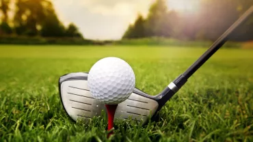 Pallina da golf su tee con mazza in primo piano