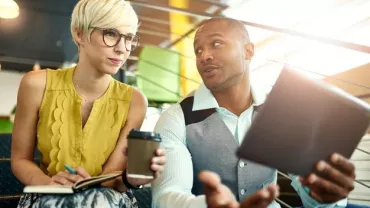 Due persone discutono in un ufficio, una con un tablet.