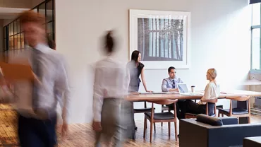 Persone in ufficio moderno con tavolo e laptop.