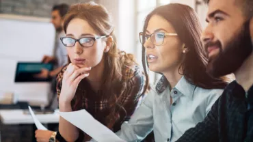 Gruppo di persone concentrate davanti a un computer alla scrivania.