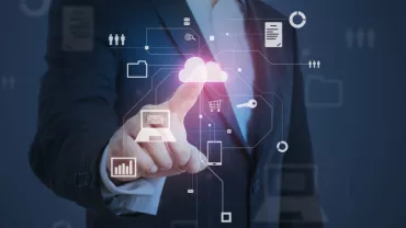Persona in abito formale tocca un'icona di cloud su uno schermo tecnologico.