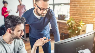 Due persone lavorano al computer in un ufficio moderno.