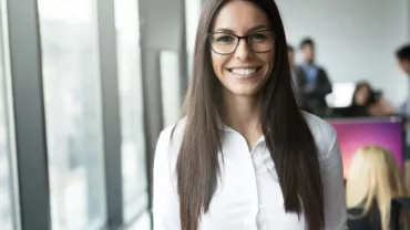 Persona in ufficio, sorridente di fronte alla telecamera