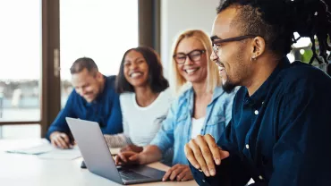 Gruppo di persone che sorridono e lavorano al computer.