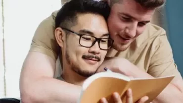 Due persone leggono un libro insieme con affetto.