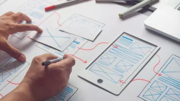 Persona che disegna un wireframe su un foglio con un tablet.