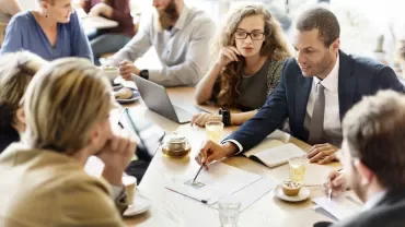 Riunione di lavoro con persone sedute intorno a un tavolo.