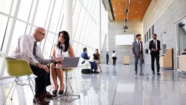 Persone in abiti formali in un moderno atrio ufficio.