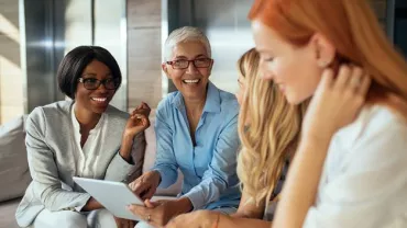 Gruppo di persone sorridenti in una conversazione, con un tablet.