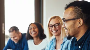 Gruppo di persone che sorridono durante una riunione.
