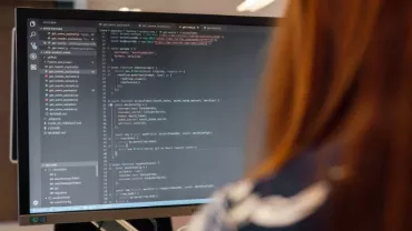 Persona al computer con codice sullo schermo.