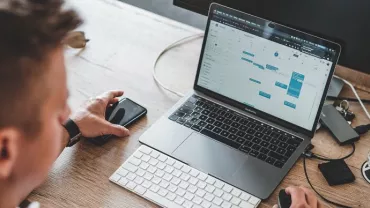 Persona al lavoro su laptop con calendario aperto.