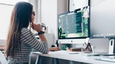 Persona al computer in ufficio moderno con schermo ampio.