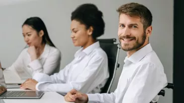 Tre persone lavorano al computer in ufficio.