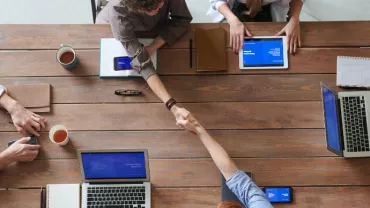 Vista dall'alto di persone che discutono e lavorano attorno a un tavolo in ufficio.