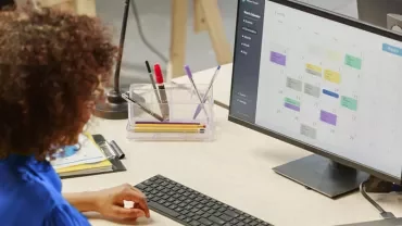 Persona in ufficio al computer controlla un calendario digitale.