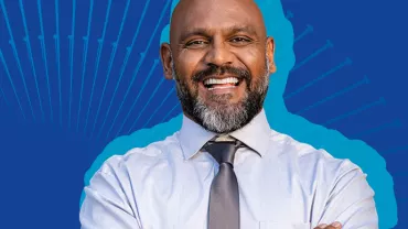 Persona sorridente in camicia e cravatta su sfondo blu.