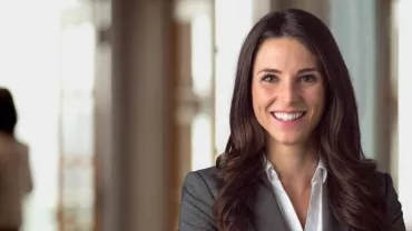 Persona sorridente in ufficio con sfondo sfocato.