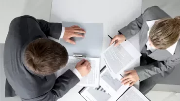 Due persone esaminano documenti in un ufficio.