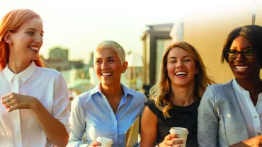 Gruppo di persone sorridenti con caffè all'aperto.