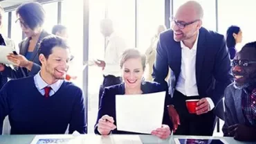 Gruppo di persone in riunione, sorridenti.