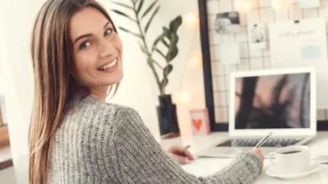 Persona sorridente al lavoro a un computer portatile.