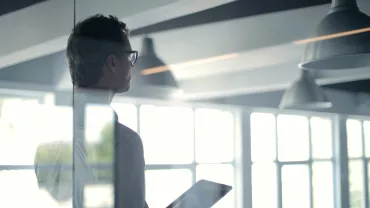 Persona con tablet in un ufficio moderno con ampie finestre.