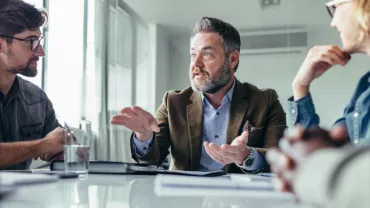 Gruppo di persone che discute in riunione d'ufficio.