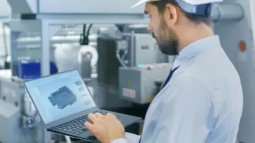 Ingegnere che lavora con un laptop in una fabbrica.