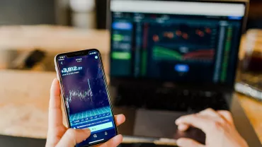 Smartphone e laptop con grafici di mercato.