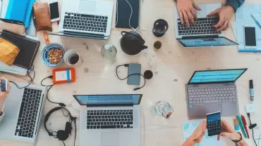Persone lavorano insieme su laptop e dispositivi mobili a un tavolo