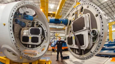 Lavoratore controlla grandi macchine industriali in un impianto.