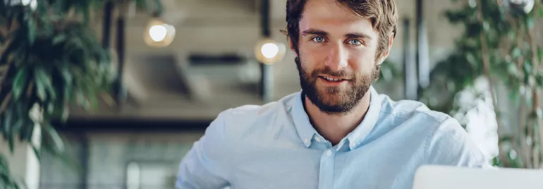 Persona sorridente in ufficio con laptop.