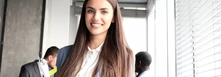 Persona sorridente con capelli lunghi, in un ufficio.