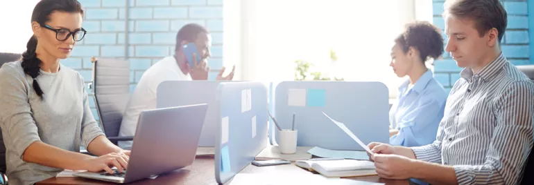 Persone sedute a lavorare su computer in un ufficio moderno.