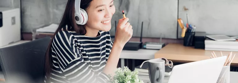 Persona con cuffie davanti a un laptop, sorridente.