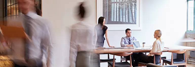 Persone in ufficio moderno con tavolo e laptop.