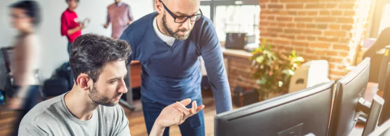 Due persone lavorano al computer in un ufficio moderno.