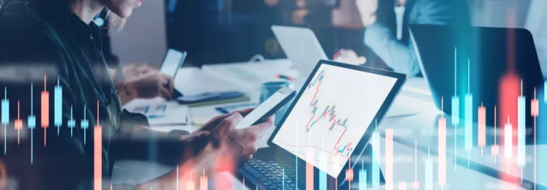 Persone lavorano al computer con grafici finanziari sullo schermo.