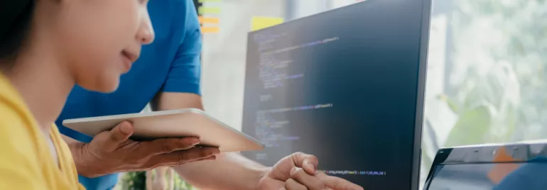 Persona che lavora al computer con codice sullo schermo.