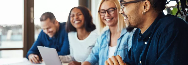Gruppo di persone che sorridono e lavorano al computer.
