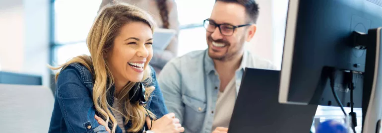 Persone che ridono e lavorano insieme al computer in un ufficio.