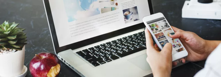 Persona che usa smartphone e laptop, con una mela e una pianta a lato.