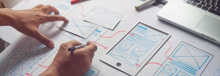 Persona che disegna un wireframe su un foglio con un tablet.