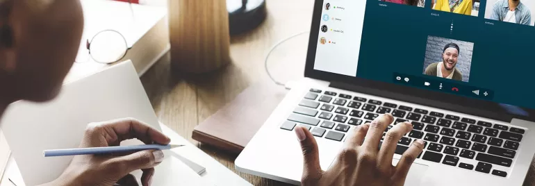 Persona che partecipa a una videochiamata su laptop con appunti.