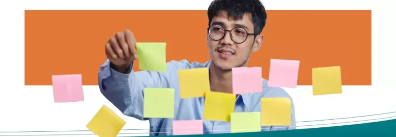 Persona con occhiali sistemando post-it colorati su un vetro.