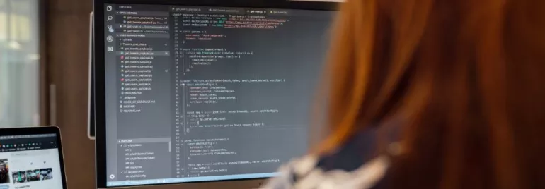 Persona al computer con codice sullo schermo.