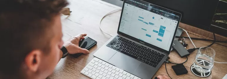 Persona al lavoro su laptop con calendario aperto.