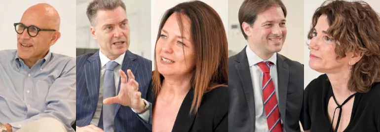 Cinque persone in abiti formali sedute e dialoganti.