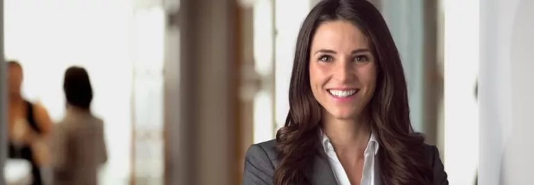 Persona sorridente in ufficio con sfondo sfocato.